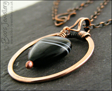Antiqued copper circle pendant with banded black heart gemstone