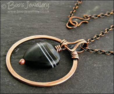 Antiqued copper circle pendant with banded black heart gemstone