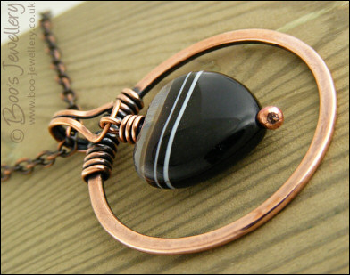 Antiqued copper circle pendant with banded black heart gemstone