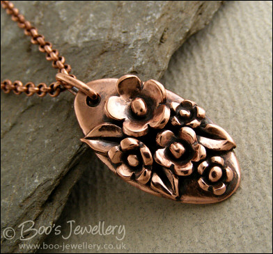 Hand sculpted oval pendant with flowers and leaves