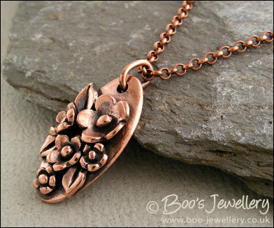 Hand sculpted oval pendant with flowers and leaves