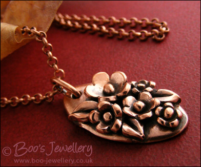 Hand sculpted oval pendant with flowers and leaves